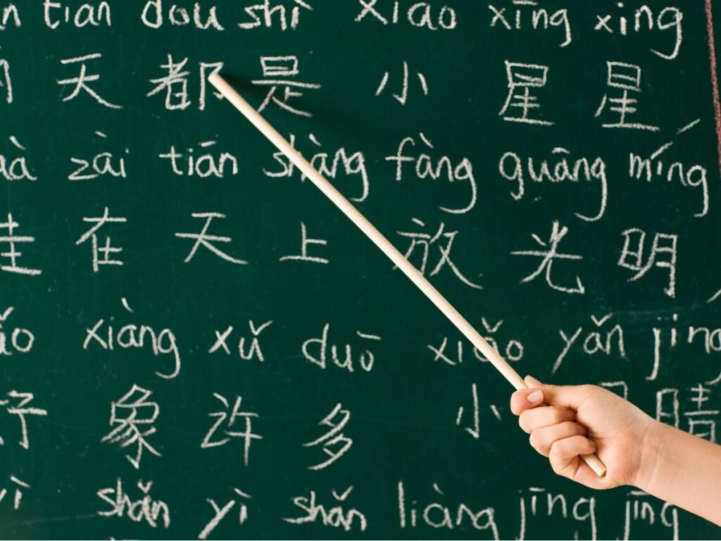 Pizarra con caracteres chinos y pinyin señalados con un puntero