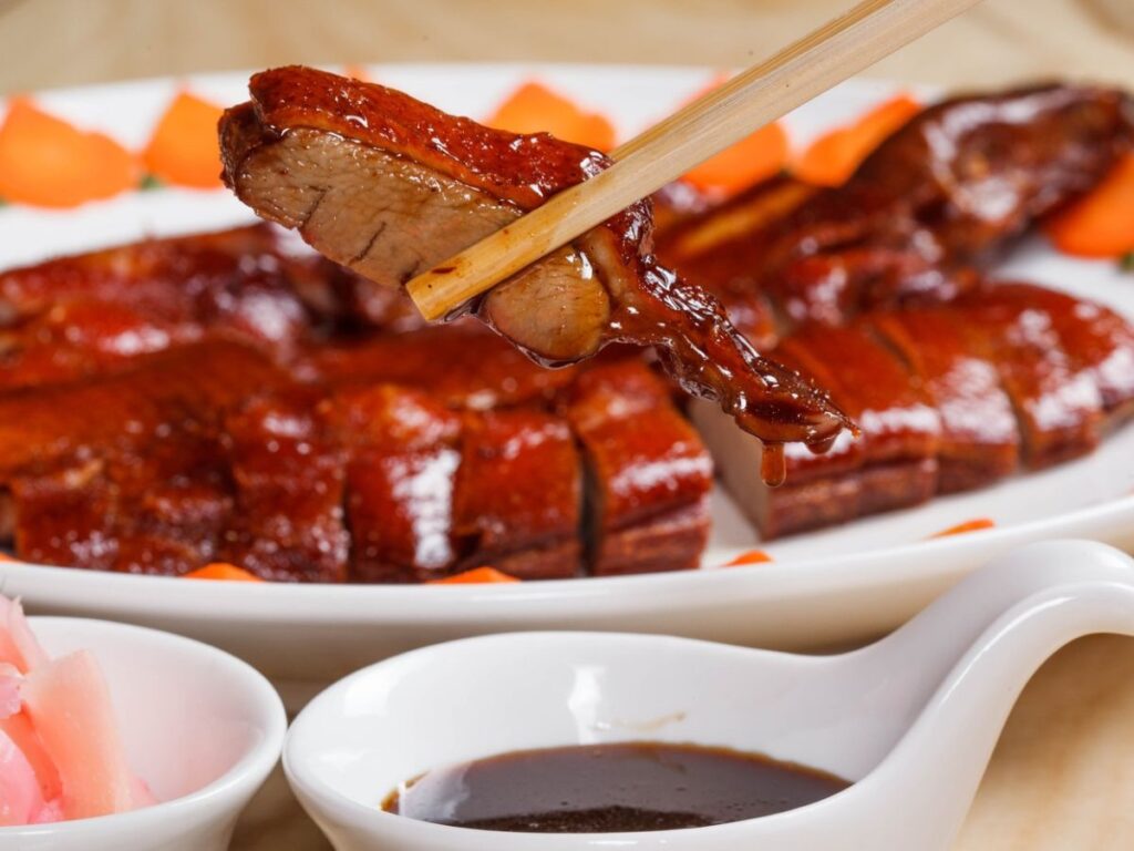 Lonchas de pato laqueado de Pekín servidas con salsa y guarnición