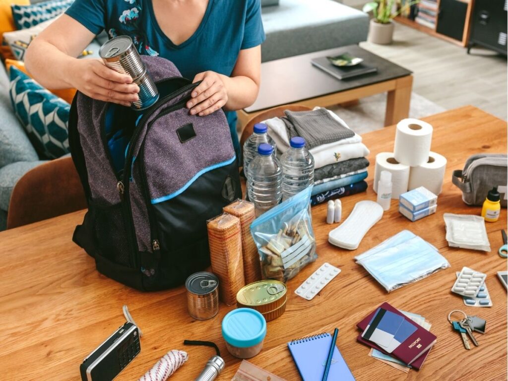 Mochila de viaje con pasaporte, documentos y artículos esenciales sobre una mesa
